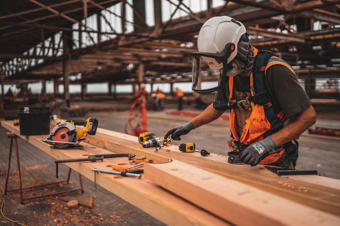 man-in-orange-and-black-vest-wearing-white-helmet-holding-yellow-and-black-power-tool-vlpum5wp5z0