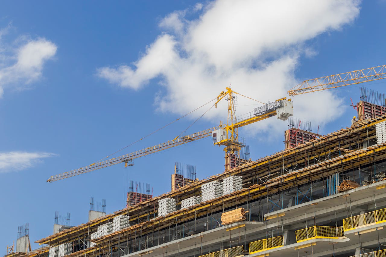 A modern construction site with cranes against a clear blue sky, showcasing urban development.